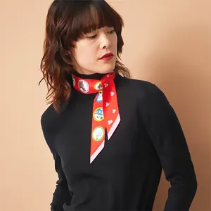 Gros plan d'un foulard en soie rouge à motif équestre porté sur un col roulé noir