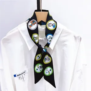 Détail d'un foulard étroit noir en soie avec imprimés cartoon noué sur un col de chemise