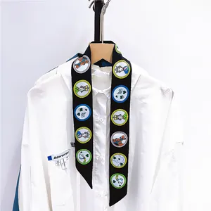 Détail d'un foulard étroit en soie noire avec des illustrations colorées de cœurs et chevaux