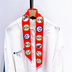 Détail d'un foulard twilly rouge à motifs de cœur noué sur un col de chemise blanc