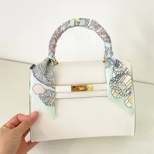 Detail of multi-color floral silk ribbon wrapped around the white leather handbag handle