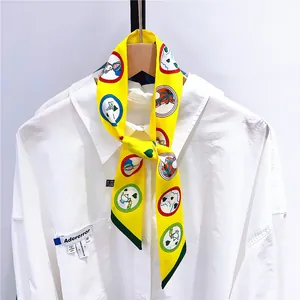 Gros plan d'un foulard en soie jaune à motifs animés noué sur un col de chemise