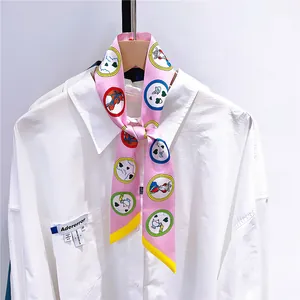 Détail d'un foulard en soie rose noué comme une cravate sur un col de chemise blanche