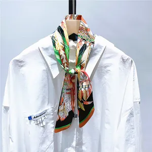 Détail d'un foulard Twilly en soie à motif plumes noué sur un col de chemise blanc
