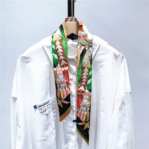 Détail d'un foulard en soie à motif plumes colorées porté sur une chemise blanche