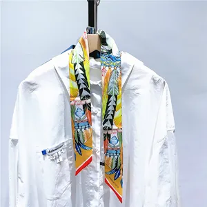 Détail d'un foulard en soie à imprimé plumes attaché sur une poche de chemise