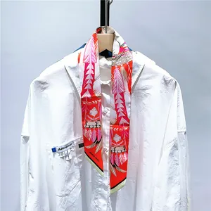 Détail d'un foulard en soie avec motifs plumes noué sur un col de chemise blanc