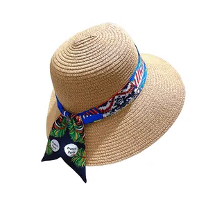 Close-up of woven straw sun hat with floral France Paris ribbon detail on white background