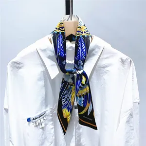 Détail d'un foulard en soie à plumes jaunes noué sur le col d'une chemise blanche