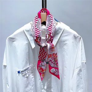 Close-up of pink floral twilly scarf tied on a white shirt collar showing silk texture