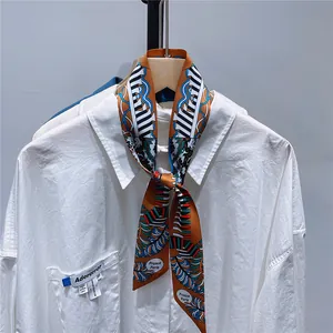 Detail of floral geometric twilly silk scarf tied on white shirt collar with Paris text