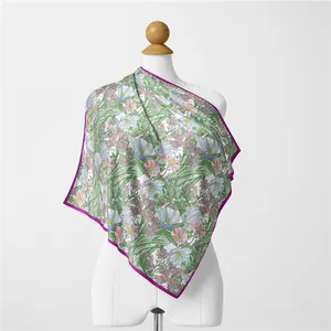Detail of floral and bird print scarf with purple edges on a white mannequin