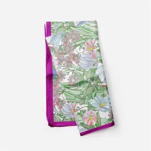 Detail of a purple floral silk scarf featuring tropical leaves and daisy patterns
