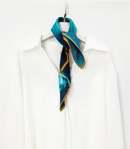 Détail d'un foulard en soie à motif d'oiseaux dorés et dégradé bleu sur col de chemise