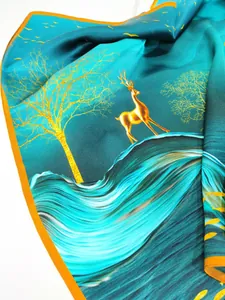 Détail d'un foulard en soie avec imprimés cerf doré et arbre sur dégradé bleu-vert