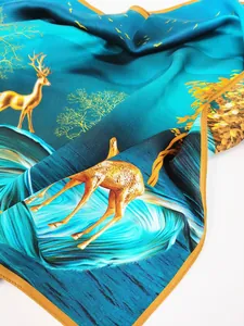 Détail d'un foulard en soie bleu foncé avec motif de cerf doré et bords raffinés