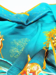 Gros plan d'un foulard en soie bleu Tiffany avec motifs de cerfs dorés et soie lisse