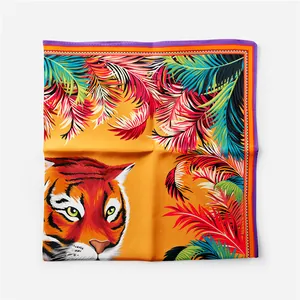 Dettaglio di un foulard di seta quadrato con stampa tigre e bordi a motivi di foglie vivaci