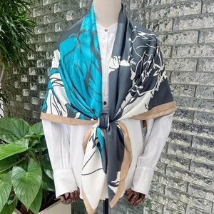 Detail of 130cm silk scarf with abstract leaf patterns in teal blue and black on a model