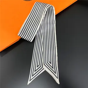 Detail of classic black and white striped silk twilly scarf on orange prop background