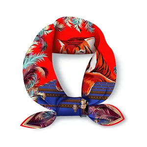 Dettaglio di un foulard in seta rossa con tigre, baule vintage e motivi di piume colorate