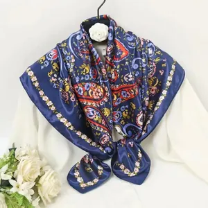 Detail of navy blue silk scarf featuring red paisley and floral patterns on white shirt