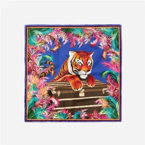 Dettaglio foulard di seta quadrato con tigre su valigia vintage e foglie di palma tropicali