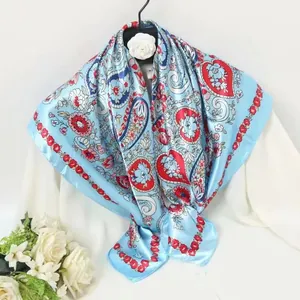 Detail of light blue paisley silk scarf with red heart floral patterns on a mannequin