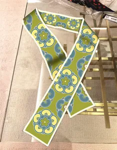 Detail of green floral paisley twilly scarf with elegant silk texture on glass surface