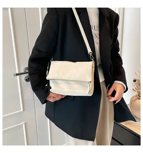 Detail of a minimalist off-white leather crossbody bag with high-quality gold hardware