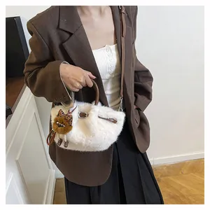 Detail van witte pluche handtas met bruine leren handvatten en een luipaard beer bedeltje