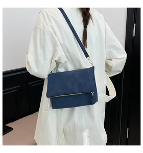Detailed view of the dark blue envelope crossbody bag with a sleek gold zipper decoration