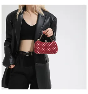 Close-up of red polka dot evening bag with gold chain and gem-set clasp detail