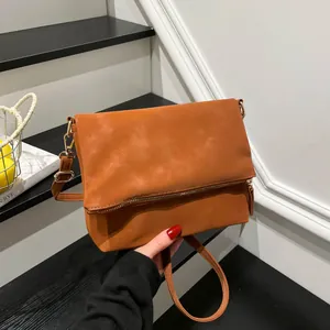 Caramel brown leather crossbody bag with gold zipper and minimalist envelope design