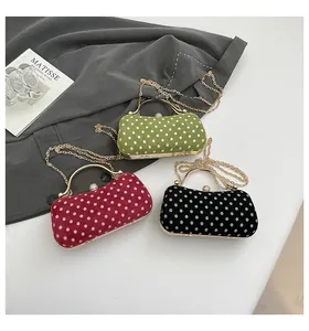 Detailed view of three polka dot clutch bags with gold handles and chain straps