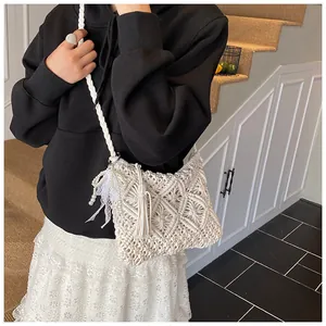 Detail of knitted crossbody bag featuring hollow diamond pattern and decorative pearl tassel