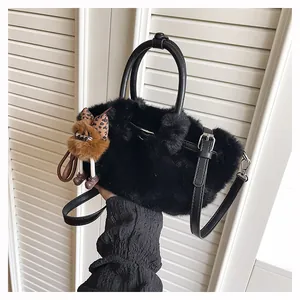 Detail van zwarte pluche handtas met schattige berenhanger en lederen handgrepen