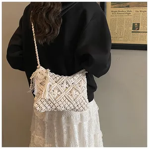 Detail of white macrame crossbody bag featuring intricate weave patterns and pearl tassels