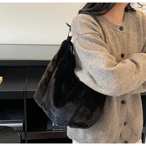Detail of a large black fluffy plush tote bag styled with a minimalist knit cardigan