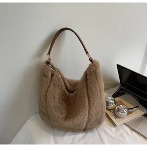 Detailed close-up of brown plush tote bag with leather strap on a cozy desktop setting
