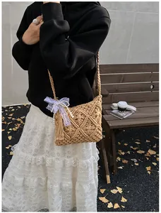 Detail of woven knit shoulder bag with lace bow, pearl charms and tassel accents