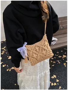 Detail of macrame shoulder bag with white lace bow and beige tassel charm decoration