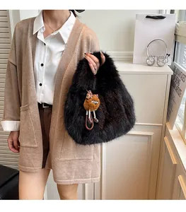 Dettaglio della texture della borsa a secchiello in peluche nera con ciondolo