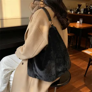 Fuzzy black plush tote bag with leather strap shown on a model in a beige coat