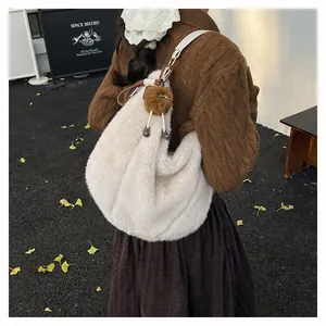 Sac hobo en peluche crème avec pendentif poupée marron lors d'une séance photo