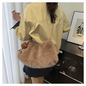 Detail of soft faux fur shoulder bag in brown with plush ball charm and strap