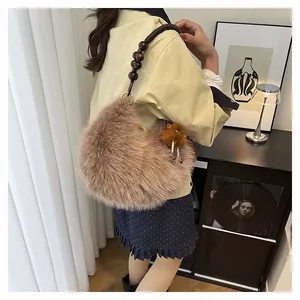 Detail of plush brown shoulder bag with dark wooden bead strap and fuzzy pompom charm