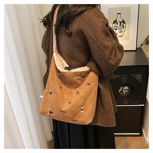 Detail of suede tote bag featuring puppy embroidery and wooden horn button closure