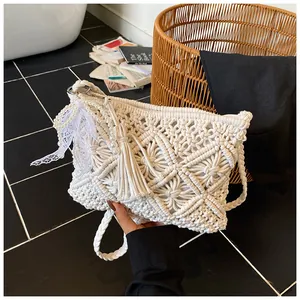 Detail of white handmade woven bag with geometric patterns, pearls, and fringe tassels