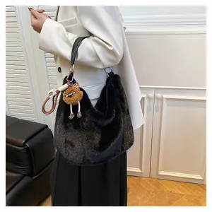 Détail du sac hobo en fausse fourrure noire avec anse en cuir et breloque lion
